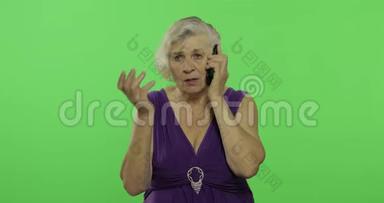一位老年妇女在智能手机上交谈。 老奶奶笑了。 铬键